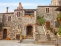 Antica piazza con case in pietra e scale fiorite, ideale per scoprire borghi da visitare in 2 giorni.