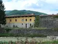 Pieve Santo Stefano: cosa vedere? Antica cinta muraria e palazzo storico affacciati sul fiume, tra colline verdi.