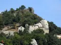 Antico eremo di Cerbaiolo, un complesso di edifici in pietra arroccato su un colle boscoso, con una croce sulla cima di una roccia.