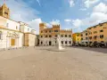 Piazza del Popolo a Grosseto, Italia, con il Duomo, il Palazzo Aldobrandeschi e case colorate.