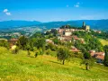 Borgo medievale in collina, un gioiello del Casentino cosa vedere. Case con tetti rossi, verde rigoglioso e un cielo azzurro intenso.
