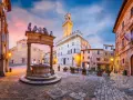 Piazza del Popolo, cuore del centro storico di Arezzo, con la sua fontana rinascimentale e il Palazzo Comunale illuminato al tramonto.