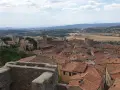 Panoramica di Massa Marittima con tetti rossi, una cattedrale imponente e colline toscane sullo sfondo.
