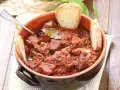 La scottiglia, un saporito stufato di carne in umido, servita in una ciotola di terracotta con fette di pane croccante.