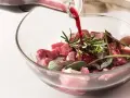 Vino rosso versato su cubetti di carne e aromi per macerare cinghiale.