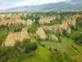 Le suggestive balze del Valdarno, scolpite dal tempo, si ergono tra verdi colline e un borgo in lontananza.