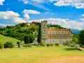 Abbazia di Sant'Antimo, un gioiello romanico immerso nel verde della Toscana, con vigneti e un borgo sullo sfondo.