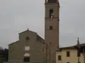 La chiesa di Sant'Agostino ad Arezzo, con il suo imponente campanile in pietra, si staglia contro un cielo nuvoloso.