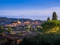 Panoramica di Montescudaio cosa vedere: borgo toscano con case in pietra, chiese e torri, immerso nel verde collinare sotto un cielo azzurro.
