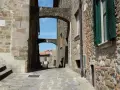 Un vicolo suggestivo a Vetulonia, tra antiche mura di pietra e archi che incorniciano il cielo azzurro. Scopri cosa vedere in questo borgo storico.