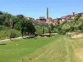Prato verde con alberi e la città di Siena sullo sfondo, con la Torre del Mangia visibile. Un luogo tranquillo, forse l'orto dei pecci siena.
