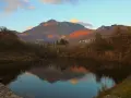 Tramonto dorato sulle montagne vicino a Villa Collemandina, con un lago che riflette il paesaggio autunnale.