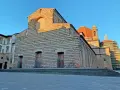 La facciata in pietra di San Lorenzo a Firenze, con la cupola arancione che domina il cielo azzurro.