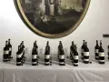 Bottiglie di vino Oreno della Tenuta Setteponti disposte su un tavolo, con un dipinto ovale sullo sfondo.