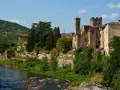 Borgo medievale di Subbiano, Arezzo, con il fiume che scorre ai suoi piedi e il verde rigoglioso che abbraccia le antiche pietre.