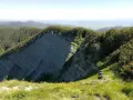 Panoramica mozzafiato sull'Alpe della Luna, con rocce stratificate che si ergono tra boschi rigogliosi e un cielo azzurro.
