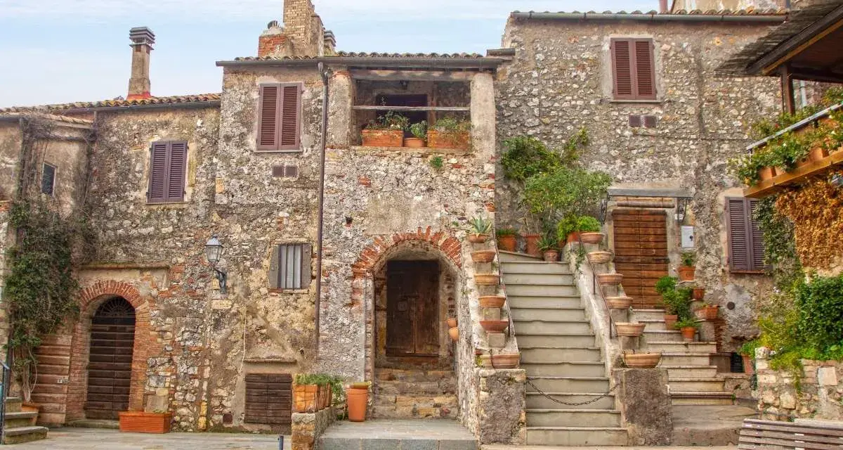 Antica piazza con case in pietra e scale fiorite, ideale per scoprire borghi da visitare in 2 giorni.