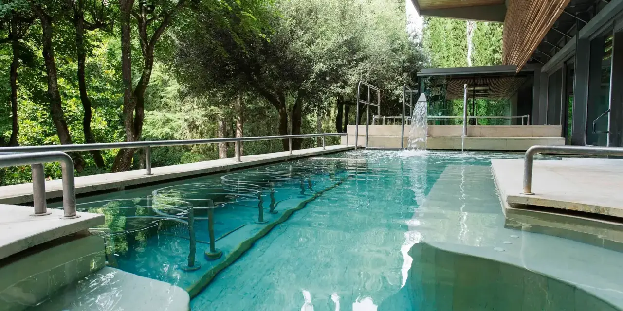Piscina termale con cascata e alberi circostanti: un'oasi di relax da scoprire tra le cose da vedere a Chianciano Terme.