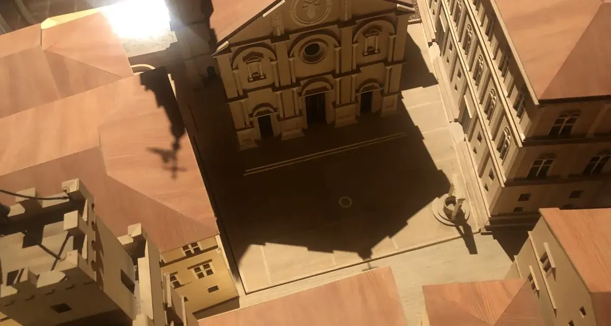 Modello in legno del duomo di Pienza e del suo complesso, con un'ombra a forma di croce che si proietta sulla piazza.