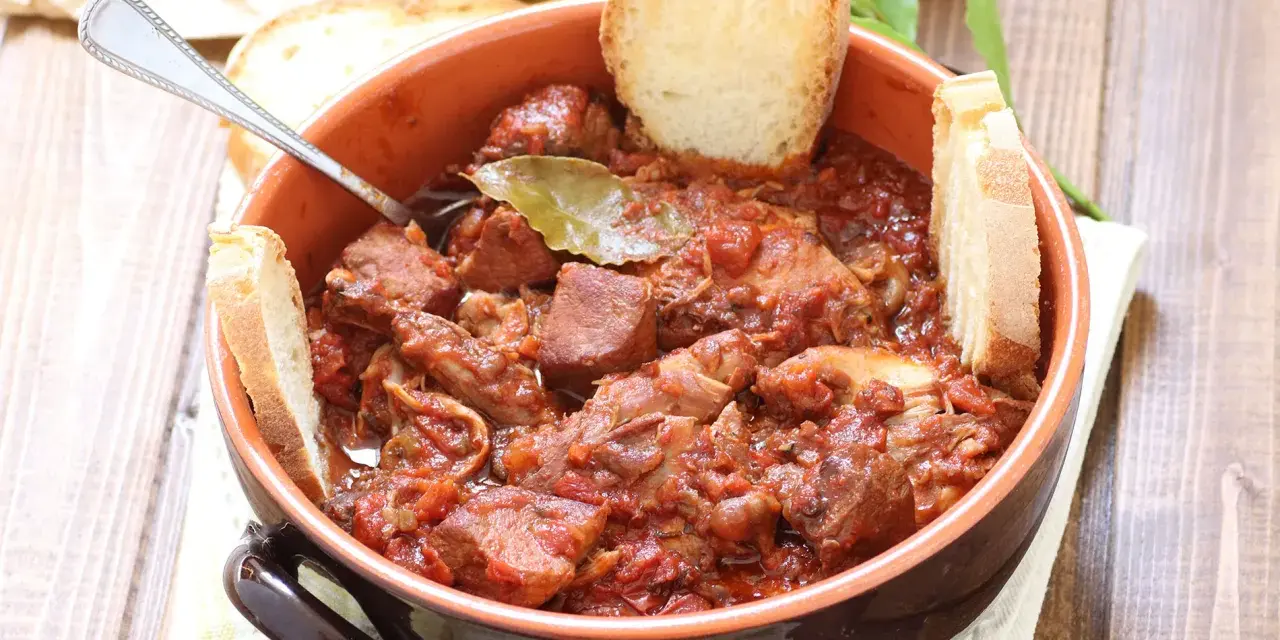 La scottiglia, un saporito stufato di carne in umido, servita in una ciotola di terracotta con fette di pane croccante.