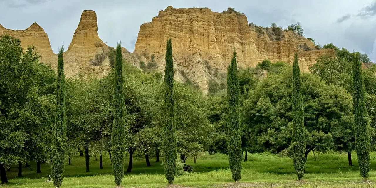 Paesaggio con calanchi ocra e cipressi slanciati, un invito a percorrere il sentiero dell'acqua zolfina.