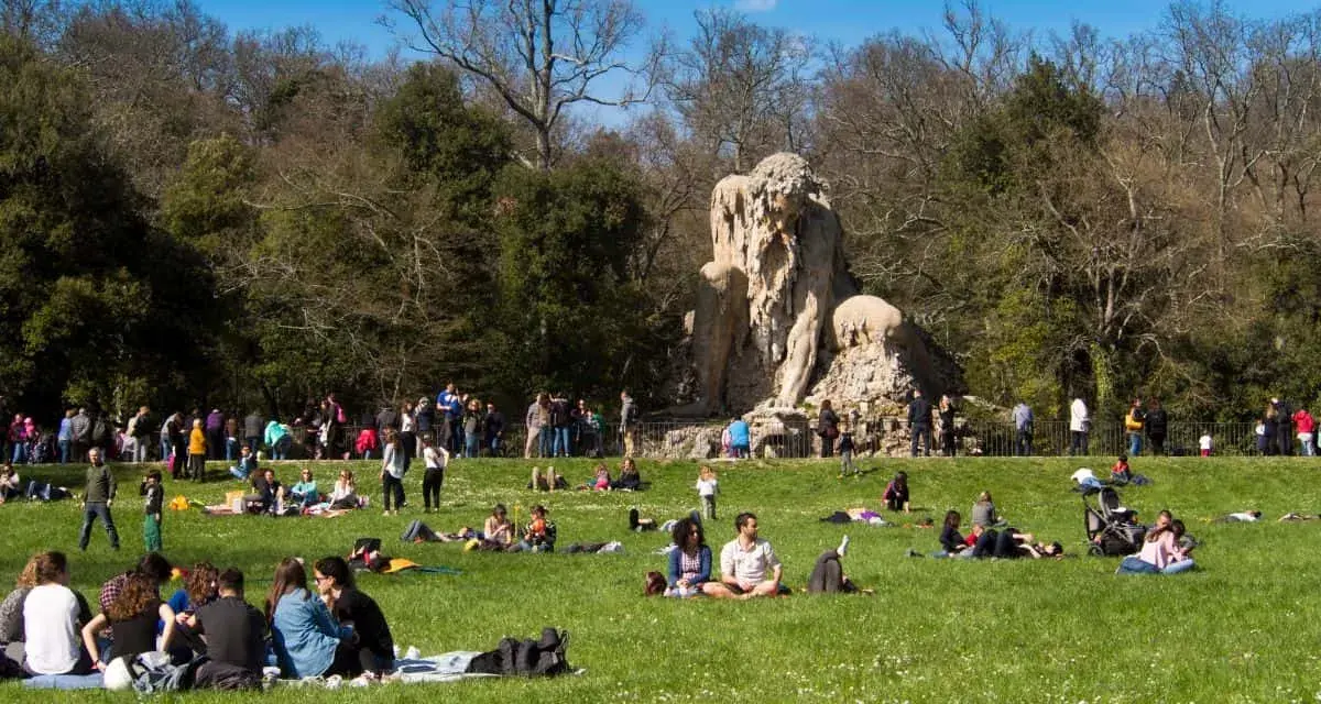 Pratolino: cosa vedere? La statua del Colosso dell'Appennino domina un prato verde affollato di persone che si godono il sole.