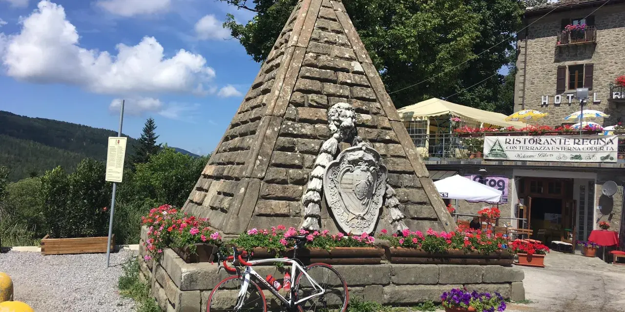 Le piramidi di Abetone, con una bici da corsa appoggiata, circondate da fiori e un ristorante.
