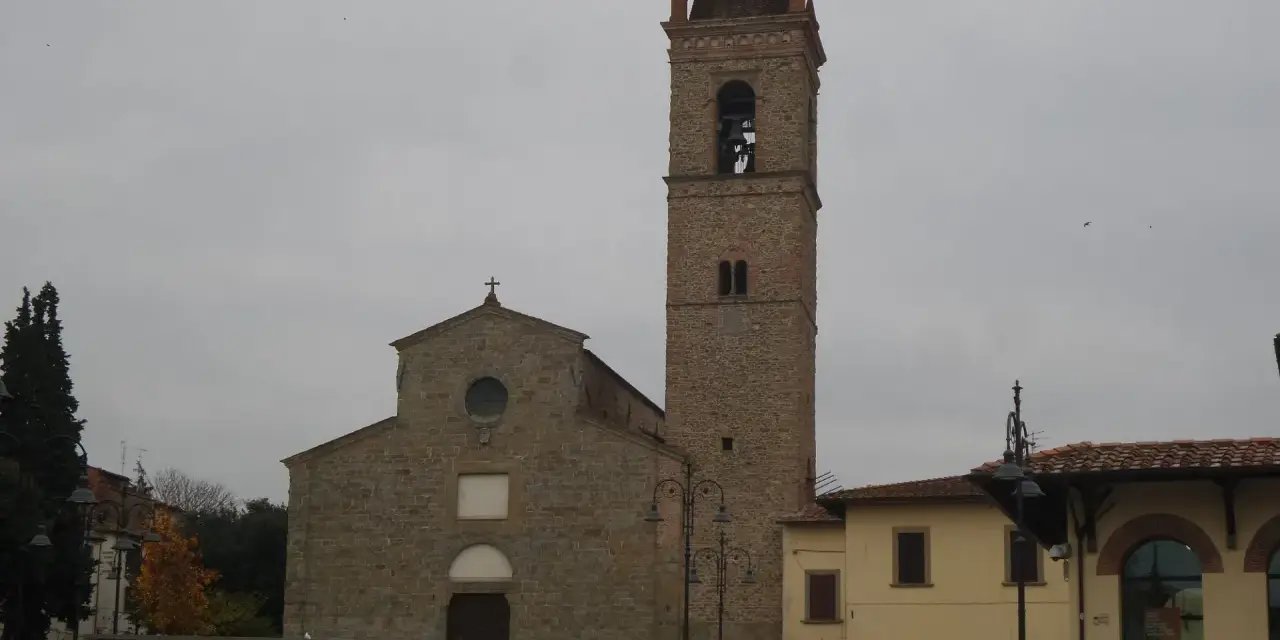 La chiesa di Sant'Agostino ad Arezzo, con il suo imponente campanile in pietra, si staglia contro un cielo nuvoloso.
