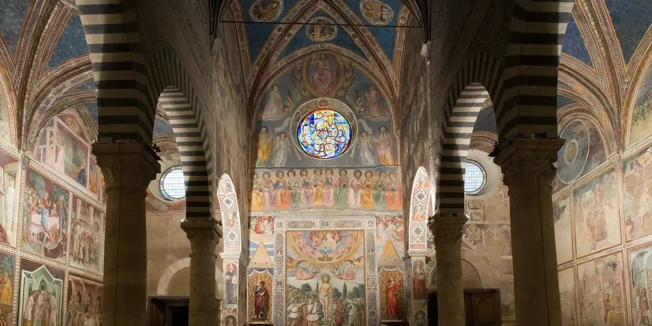 Interno del duomo di San Gimignano, con affreschi medievali che narrano storie sacre, volte a crociera a strisce bianche e nere e un rosone colorato.
