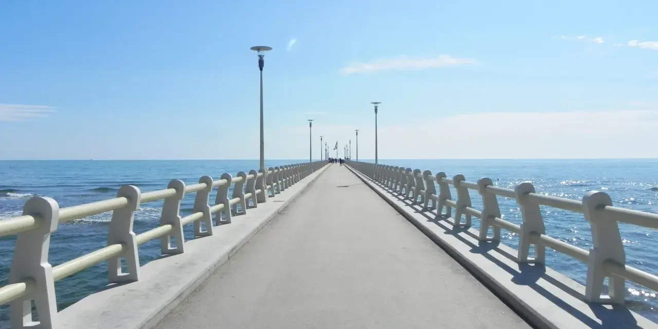 Il pontile di Forte dei Marmi si estende verso il mare azzurro sotto un cielo limpido, invitando a una passeggiata.