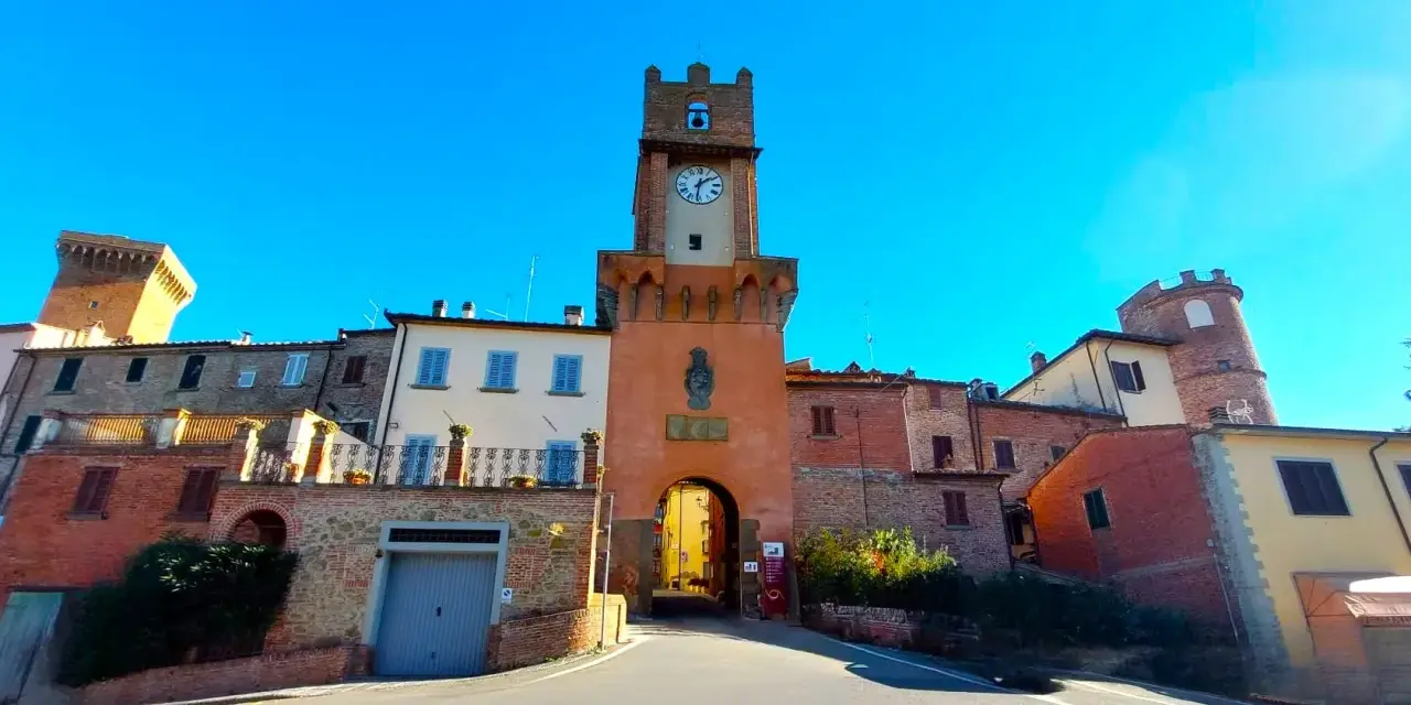 Torre dell'orologio a Marciano Italia, con un arco medievale e case in pietra.