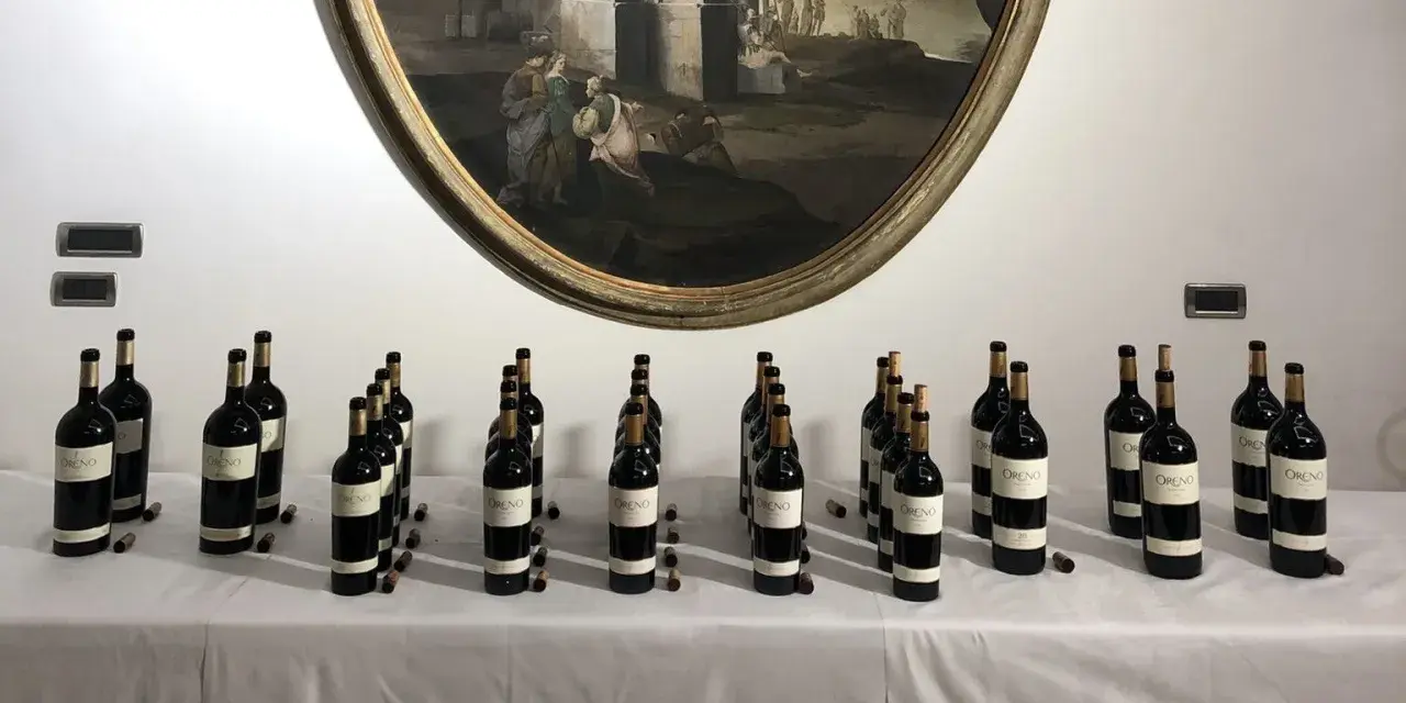 Bottiglie di vino Oreno della Tenuta Setteponti disposte su un tavolo, con un dipinto ovale sullo sfondo.