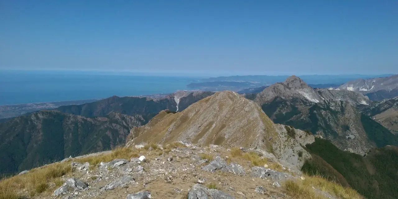 Panoramica mozzafiato dal monte Argegna, con il mare azzurro all'orizzonte e le cime rocciose che si stagliano contro il cielo limpido.