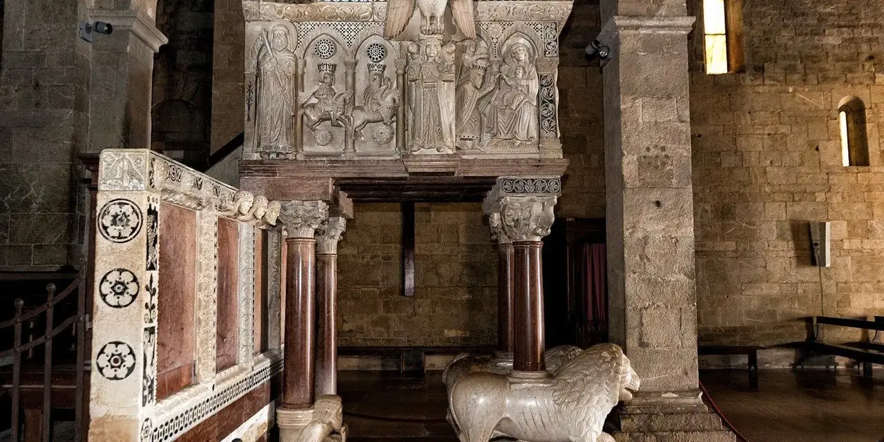 Interno del duomo di Barga con un leone in marmo e un pulpito scolpito.