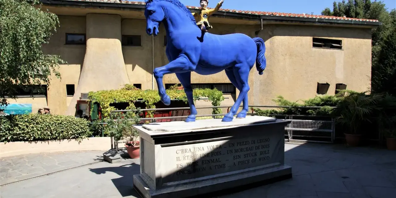 Un cavallo blu con Pinocchio a cavalcioni, simbolo del paese di Collodi. La statua è posta su un piedistallo con la frase "C'era una volta... un pezzo di legno" in più lingue.