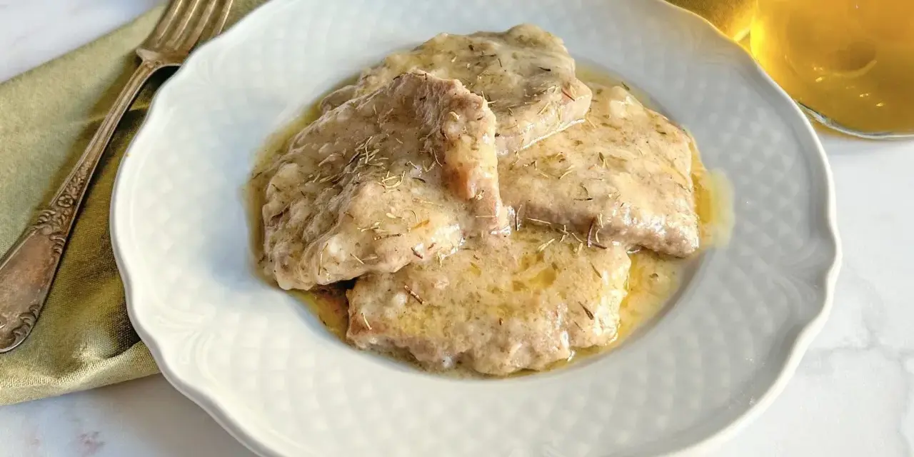 Grifi in umido, teneri e succulenti, serviti su un piatto bianco con forchetta e bicchiere di vino.