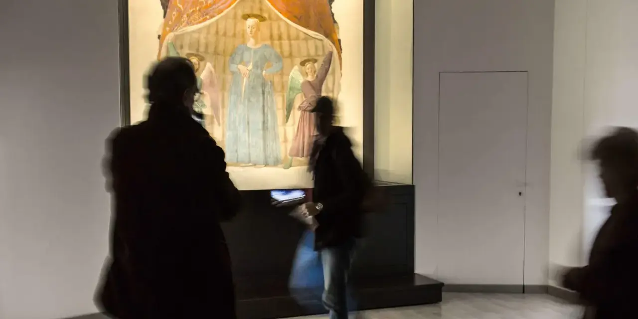 Un'opera d'arte a Monterchi, cosa vedere: visitatori ammirano un affresco con figure sacre in un museo.