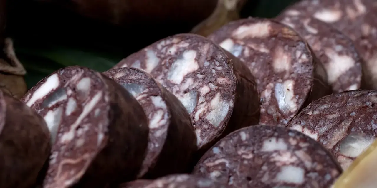 Fette di biroldo toscano, un salume scuro con striature bianche, pronto per essere gustato.