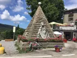 Le piramidi di Abetone, con una bici da corsa appoggiata, circondate da fiori e un ristorante.