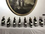 Bottiglie di vino Oreno della Tenuta Setteponti disposte su un tavolo, con un dipinto ovale sullo sfondo.