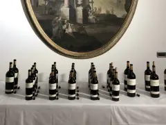 Bottiglie di vino Oreno della Tenuta Setteponti disposte su un tavolo, con un dipinto ovale sullo sfondo.