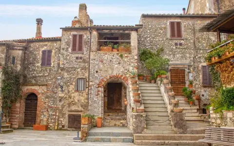 Antica piazza con case in pietra e scale fiorite, ideale per scoprire borghi da visitare in 2 giorni.