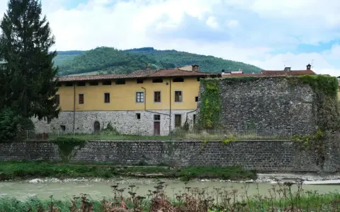 Pieve Santo Stefano: cosa vedere? Antica cinta muraria e palazzo storico affacciati sul fiume, tra colline verdi.