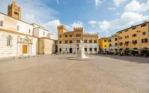 Piazza del Popolo a Grosseto, Italia, con il Duomo, il Palazzo Aldobrandeschi e case colorate.