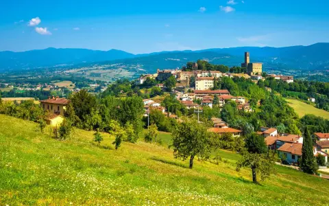 Borgo medievale in collina, un gioiello del Casentino cosa vedere. Case con tetti rossi, verde rigoglioso e un cielo azzurro intenso.