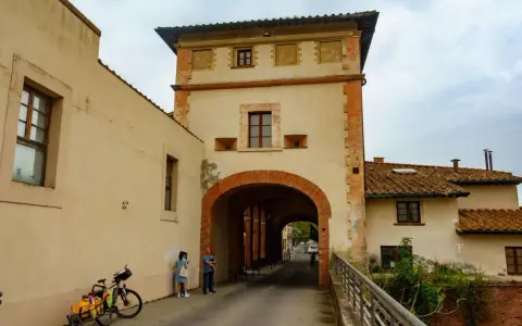 Un arco imponente a Santa Maria a Monte, con una coppia che osserva la strada. Una bici carica attende.