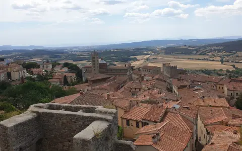 Panoramica di Massa Marittima con tetti rossi, una cattedrale imponente e colline toscane sullo sfondo.