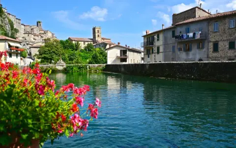 Fiori rossi in primo piano, con il borgo di Santa Fiora e il suo fiume sullo sfondo.