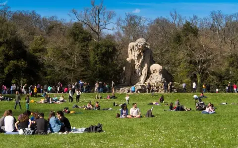 Pratolino: cosa vedere? La statua del Colosso dell'Appennino domina un prato verde affollato di persone che si godono il sole.