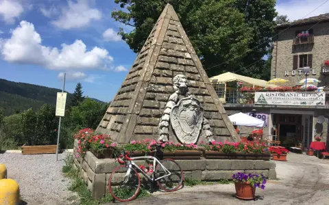 Le piramidi di Abetone, con una bici da corsa appoggiata, circondate da fiori e un ristorante.